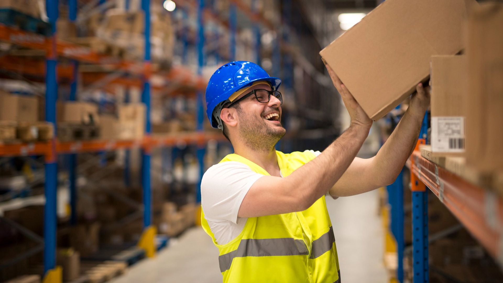 smiling-warehouse-worker-moving-boxes-shelf